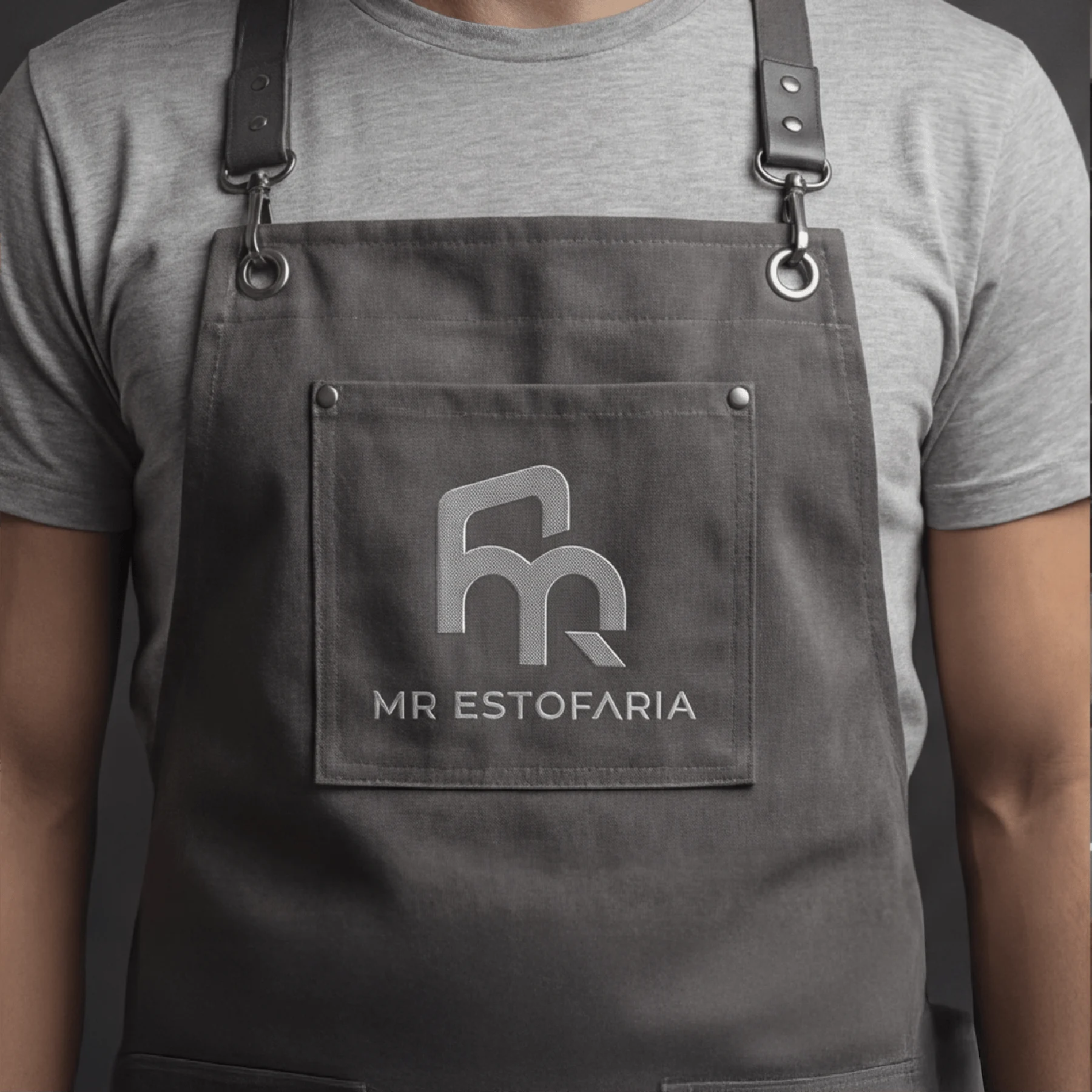 Monograma MR Estofaria aplicado a um avental cinza.