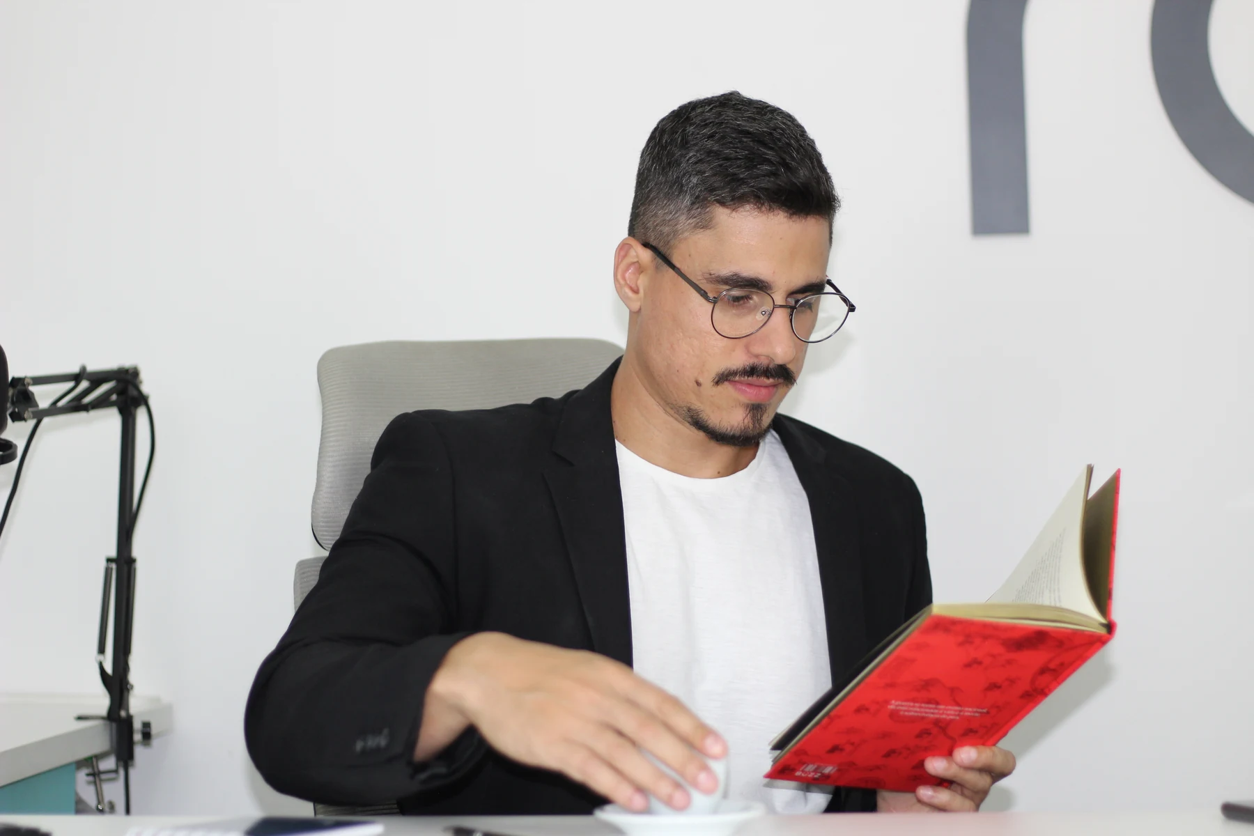 Rafael folheando um livro à mesa do estúdio.